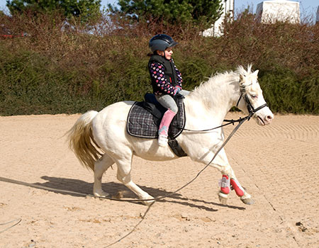 Pige får undervisning på pony